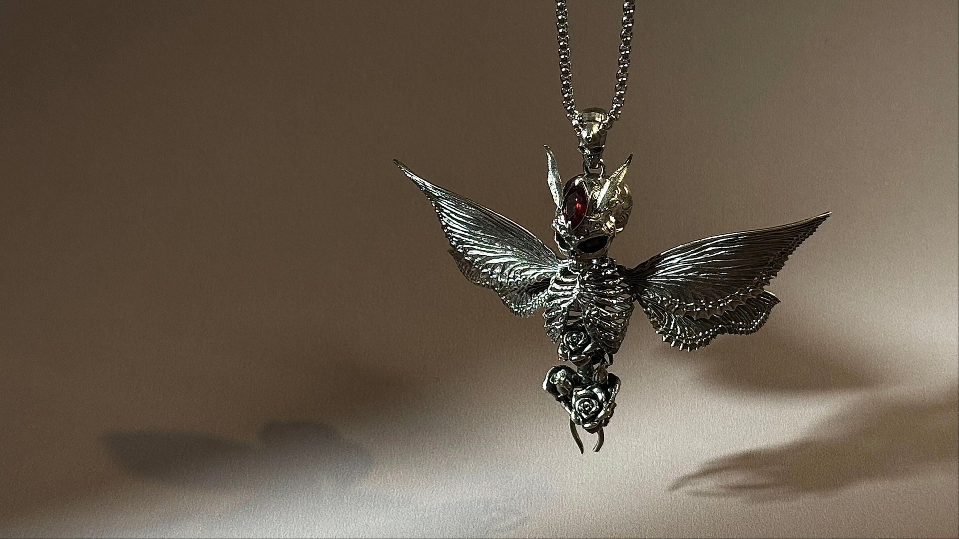 Sterling silver skull moth pendant necklace with red gemstone and rose detail
