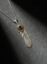 Handcrafted sterling silver feather pendant necklace with brass accent and a red gemstone centerpiece.