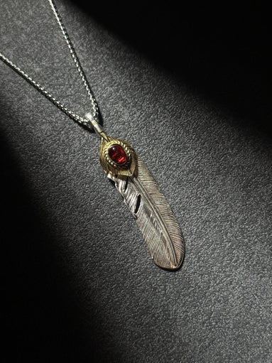 Handcrafted sterling silver feather pendant necklace with brass accent and a red gemstone centerpiece.
