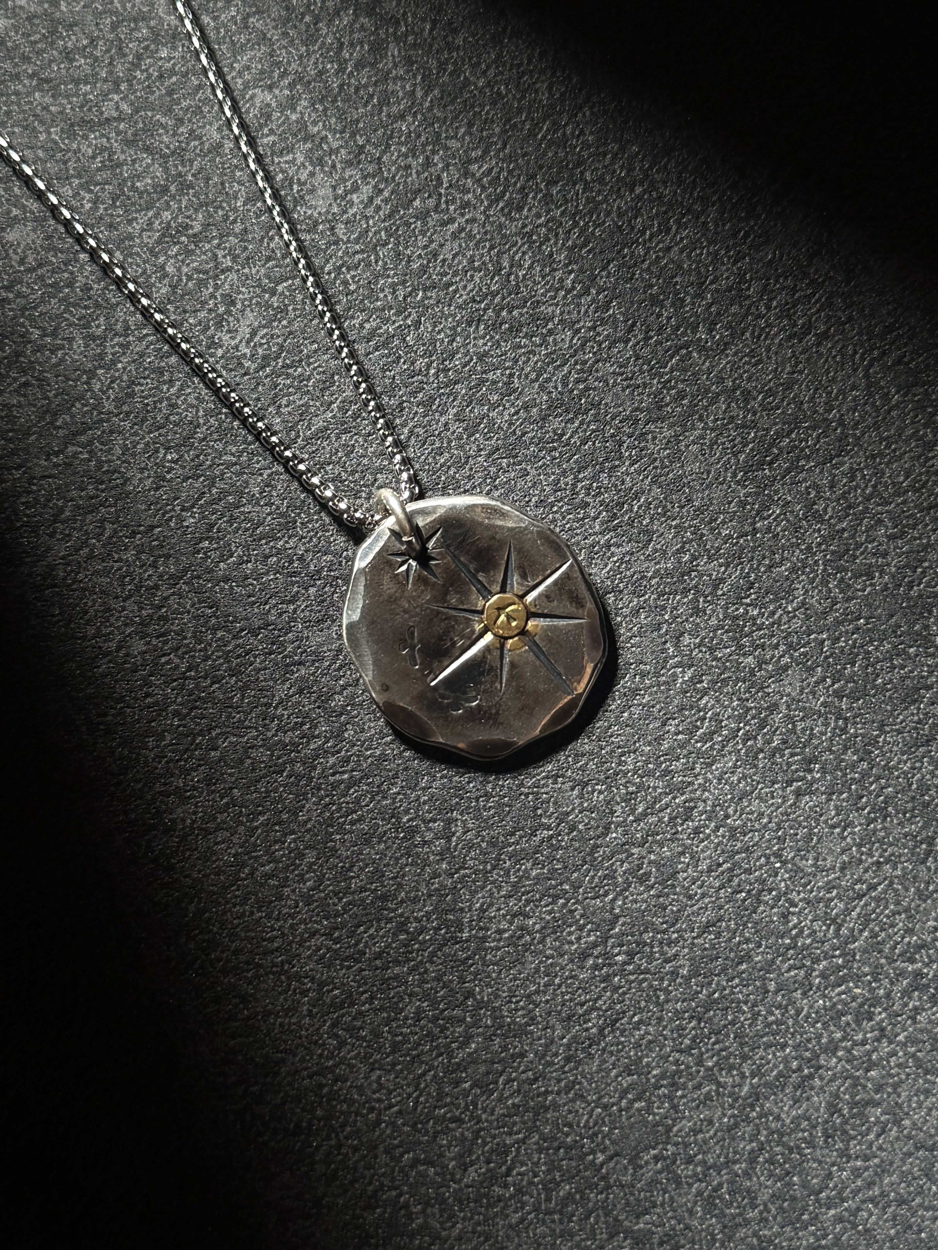 North Star sterling silver pendant necklace with brass center on dark textured background