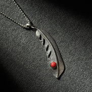 Handcrafted sterling silver feather pendant necklace featuring a natural red coral accent.