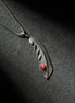 Handcrafted sterling silver feather pendant necklace featuring a natural red coral accent.