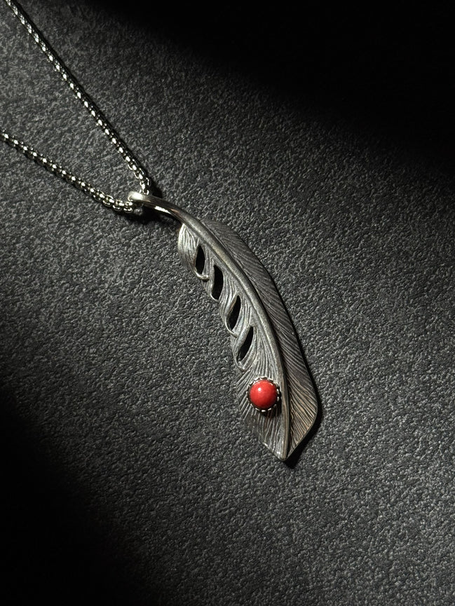 Handcrafted sterling silver feather pendant necklace featuring a natural red coral accent.