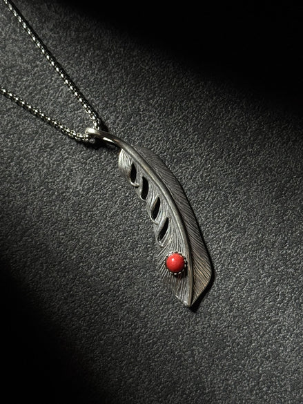 Handcrafted sterling silver feather pendant necklace featuring a natural red coral accent.