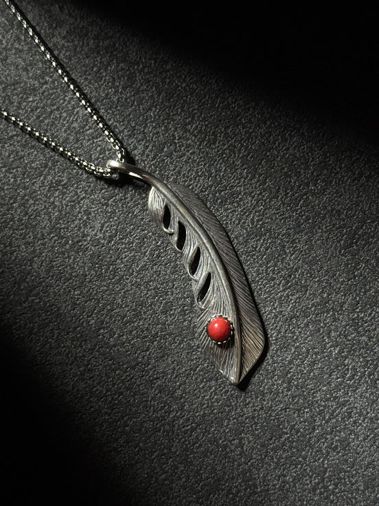 Handcrafted sterling silver feather pendant necklace featuring a natural red coral accent.